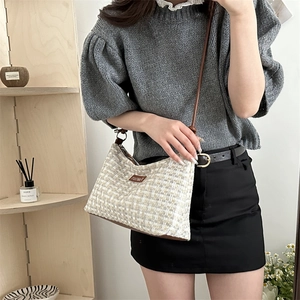 Plaid texture hobo bag with brown leather trim worn by a model in a minimalist home setting