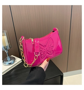 Détail du sac baguette en cuir verni fuchsia avec gaufrage papillon et chaîne dorée