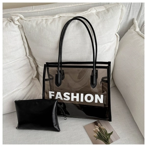 Close-up of transparent PVC tote bag with black trim and inner pouch on white sofa