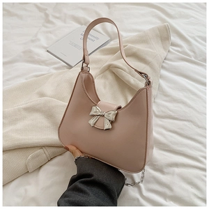 Detail of light pink crescent bag featuring silver bow buckle and decorative metal chain