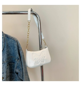 Gros plan du sac porté épaule en cuir verni blanc avec papillon 3D et chaîne dorée
