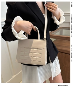 Dettaglio di una borsa beige trapuntata a quadri indossata da una modella in stile minimal