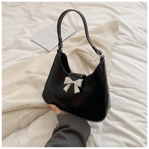 Close-up of black patent leather bag featuring a silver bow buckle and glossy texture