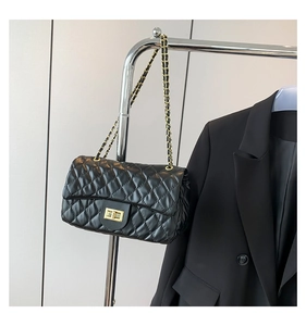 Close-up of black quilted leather shoulder bag with gold chain and turn-lock detail