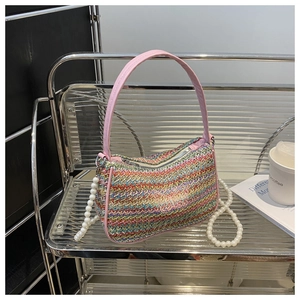 Detail of rainbow woven bag featuring butterfly embroidery and elegant pearl chain strap