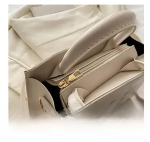 Dettaglio dell'interno a scomparti e della cerniera dorata della borsa a mano beige