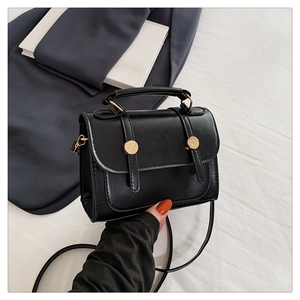 Dettaglio della borsa mini squadrata nera vintage con fibbie dorate e manico superiore