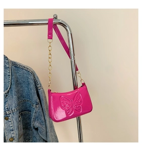 Détail du sac en cuir verni rose avec motif papillon embossé et bandoulière en chaîne