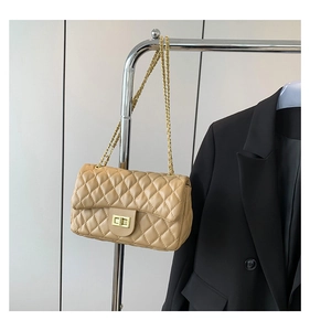 Close-up of beige quilted crossbody bag with gold chain and metal twist lock