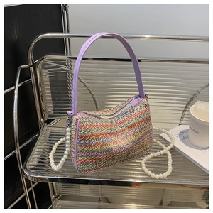 Detail of colorful woven straw bag with butterfly motif and pearl crossbody chain strap