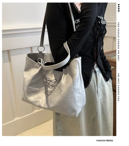 Close-up of metallic silver tote bag with decorative chain and bow on a model
