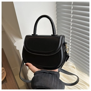 Detail of black leather saddle bag with gold metal hardware and top handle design