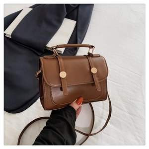 Dettaglio della borsa a tracolla in ecopelle marrone stile inglese con fibbia dorata