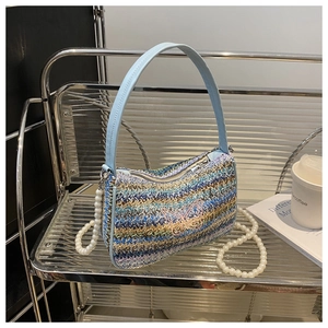 Detail of colorful woven straw bag with pink butterfly embroidery and pearl strap handle