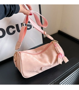 Detailed macro view of pink velvet cylindrical crossbody bag with gold hardware buckle