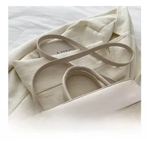 Dettaglio borsa a mano trapuntata beige con cuciture fini e accessori in oro lucido