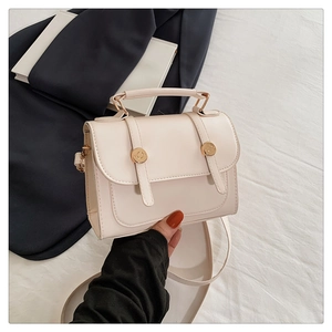 Dettaglio di una borsa a mano avorio con fibbie dorate e manico rigido superiore