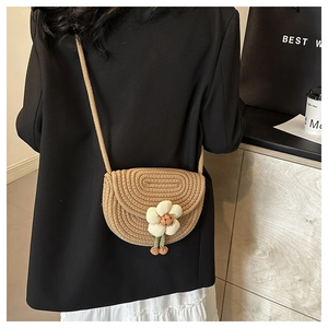 Close-up of khaki woven saddle bag with white fabric flower and wooden bead detail