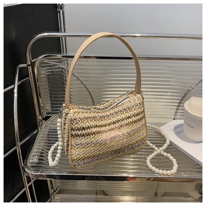 Detail of woven straw crossbody bag with pink butterfly embroidery and pearl strap