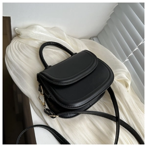 Close-up of black matte leather saddle bag with gold-tone hardware and top handle