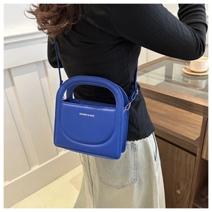 Close-up of klein blue crossbody bag with FASHION & BAGS text and matte texture