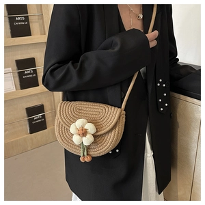 Detail of hand-woven straw crossbody bag with white 3D flower and colorful pendants