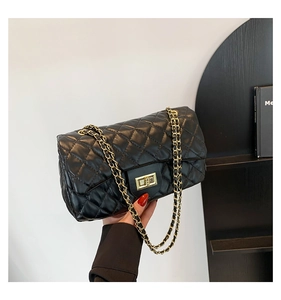 Macro shot of black quilted faux leather texture and gold chain strap on the bag
