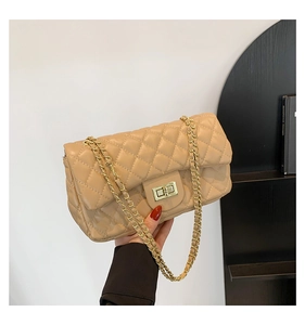 Detail of beige quilted flap bag showing golden metal twist lock and chain strap