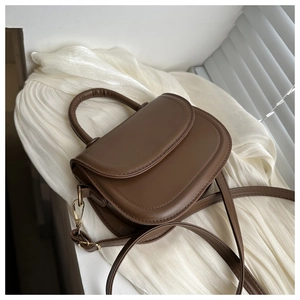Detail of a dark brown retro crossbody bag featuring a curved top handle and golden hardware