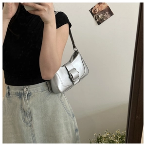 Mirror silver baguette bag with oversized buckle buckle worn over the shoulder as OOTD style