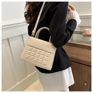 Dettaglio della trama trapuntata e delle finiture dorate sulla borsa in pelle bianca