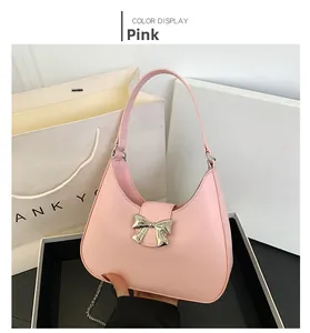 Detail of pink half-moon handbag featuring a silver metallic bow and matte leather finish