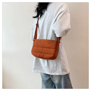 Détail d'un petit sac bandoulière orange matelassé avec une sangle en tissu réglable
