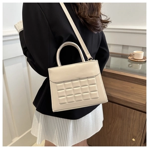 Elegante borsa a mano color crema con trama trapuntata e manico in un caffè