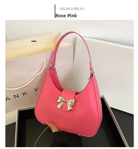 Detailed view of rose pink matte leather shoulder bag with a silver bow ornament