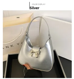 Detail of silver metallic hobo bag featuring a decorative metal bow and chain strap