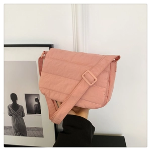 Gros plan du sac bandoulière rose matelassé avec coutures horizontales et sangle