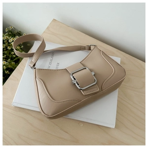 Close-up of beige leather baguette bag with silver buckle on a wooden surface