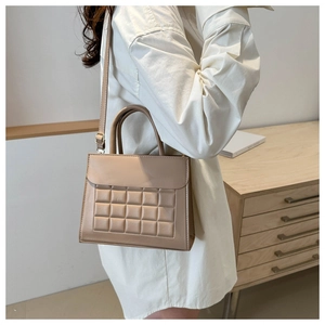 Vista dettagliata della borsa a mano beige trapuntata con manico e tracolla regolabile