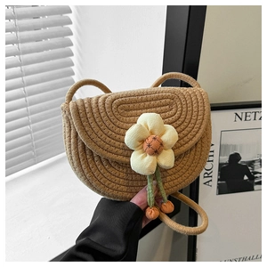 Detail of hand-woven straw crossbody bag with decorative large floral fabric accents