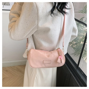 Detail shot of a pink cylinder crossbody bag with fashion tag and stylish strap