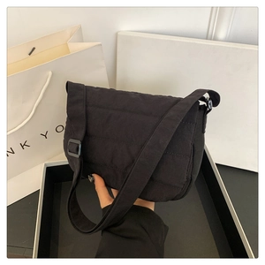 Détail de la sacoche noire matelassée avec une large bandoulière réglable en nylon