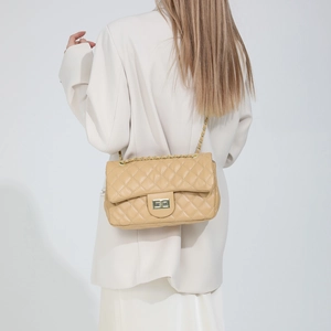 Petit sac bandoulière beige matelassé avec chaîne dorée porté sur une veste blanche
