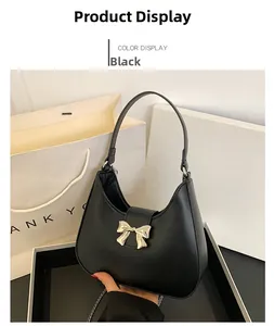 Detail of black faux leather shoulder bag featuring a silver metal bow and chain strap