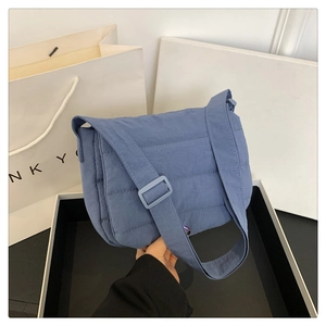 Vue détaillée d'un sac bandoulière bleu matelassé avec large sangle réglable