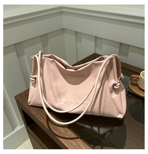Close-up of pink soft leather tote bag showing the embossed brand logo and knotted strap detail