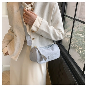 Detail view of the cylinder bag featuring embossed logo and wide woven shoulder strap