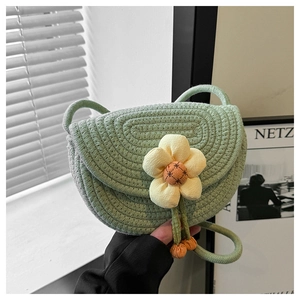 Close-up of light green woven shoulder bag featuring a 3D floral accent and spiral texture