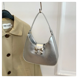 Detail of silver metallic hobo bag featuring a decorative bow-shaped metal clasp