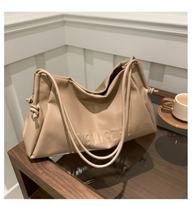 Detail of minimalist beige soft leather tote bag with side knot and embossed letters